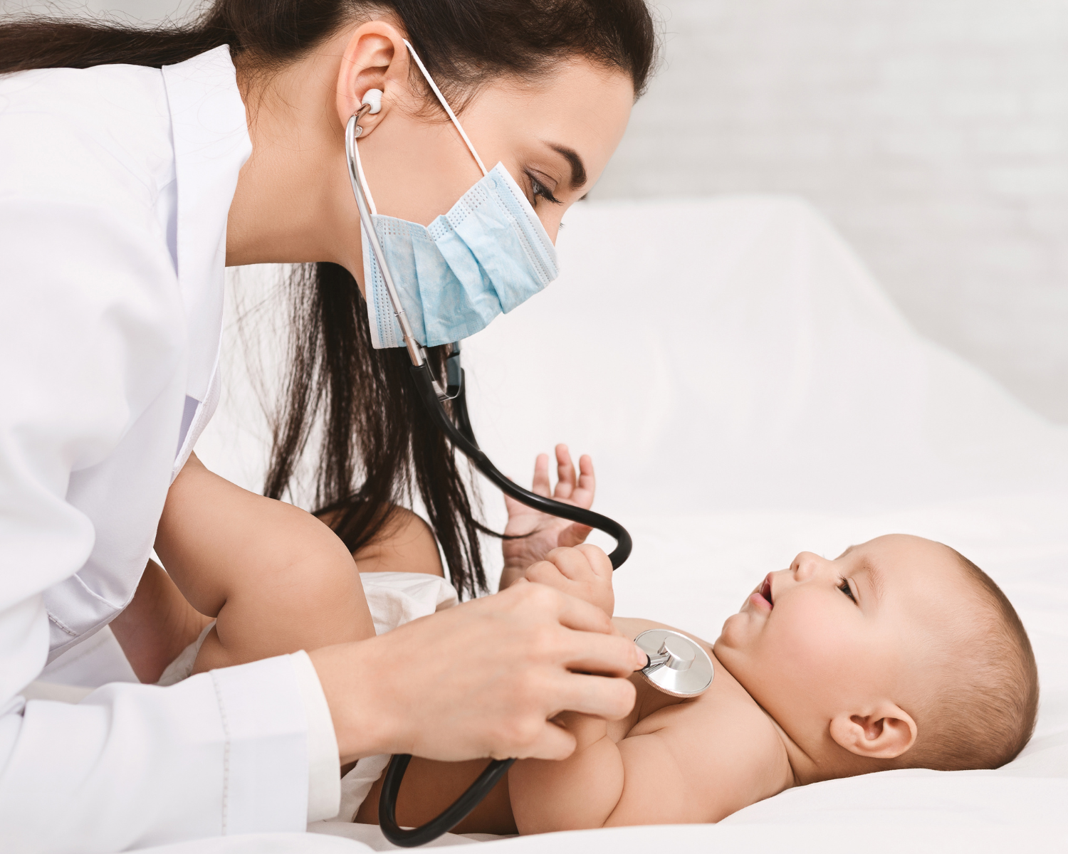 Female health provider giving a baby a health exam using a stethescope