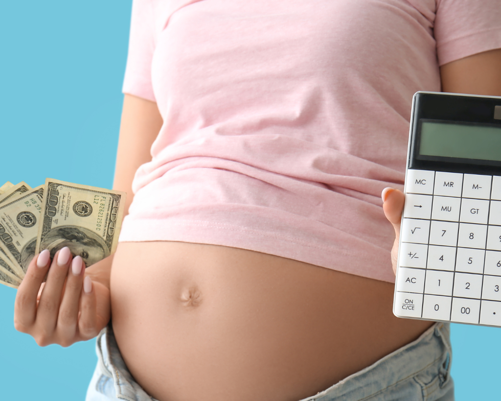 pregnant woman in a pink tshirt holding cash in one hand and a calculator in the other hand