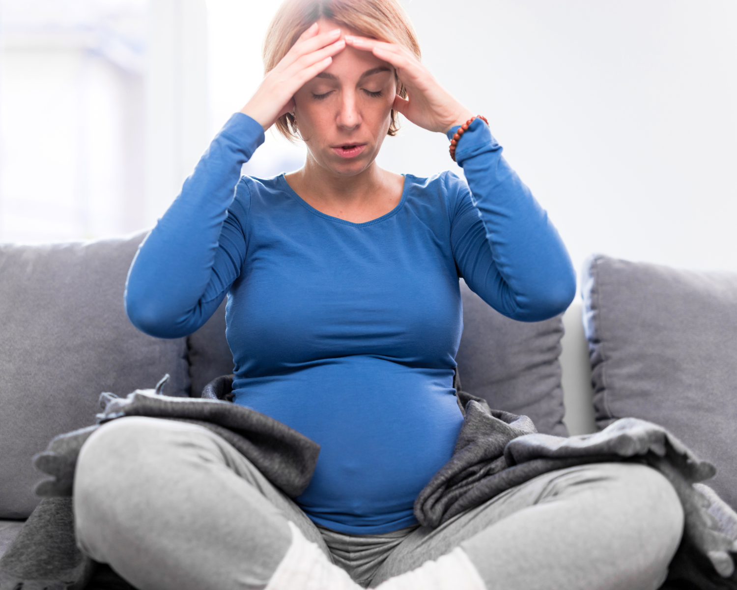 photo of a pregnant mom sitting on the couch with her hands on her head